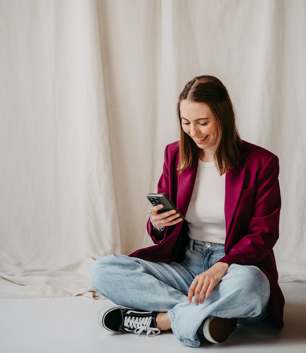 Foto von Anna mit Smartphone - sie scheint gerade etwas lustiges zu lesen.